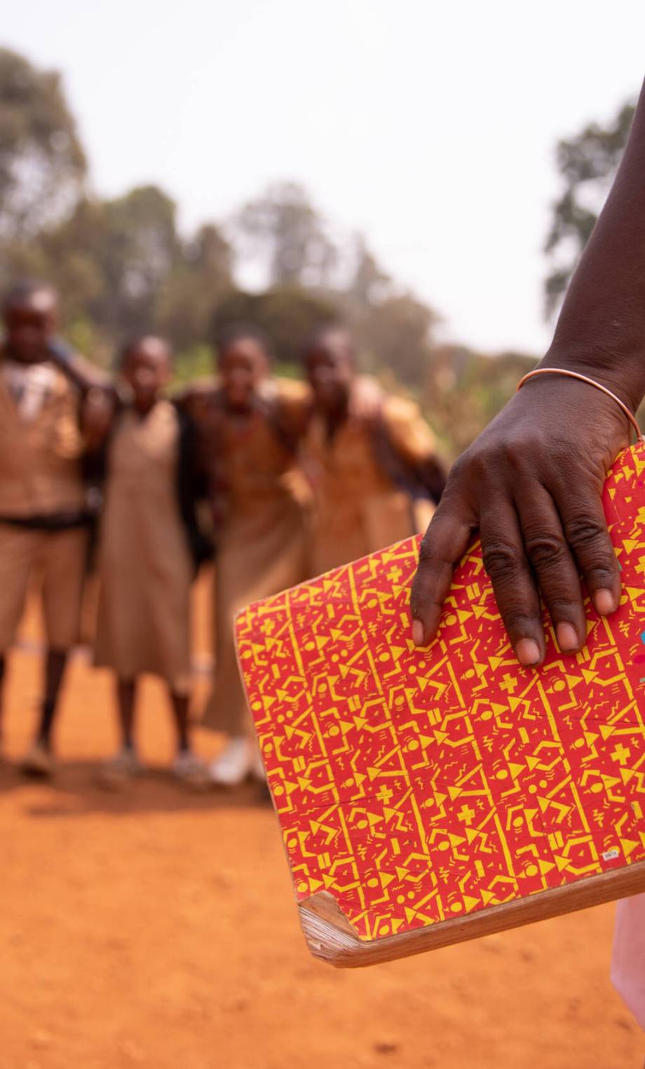 An african teacher is holding a book with her students out of focus in the background, concept of education in africa