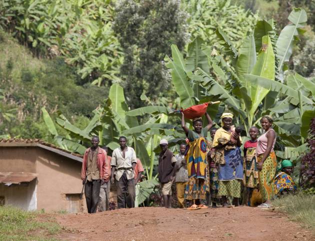 Locals gathered in a rural village setting surrounded by lush greenery