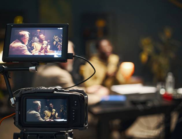 People sitting at table and recording online podcast on professional camera